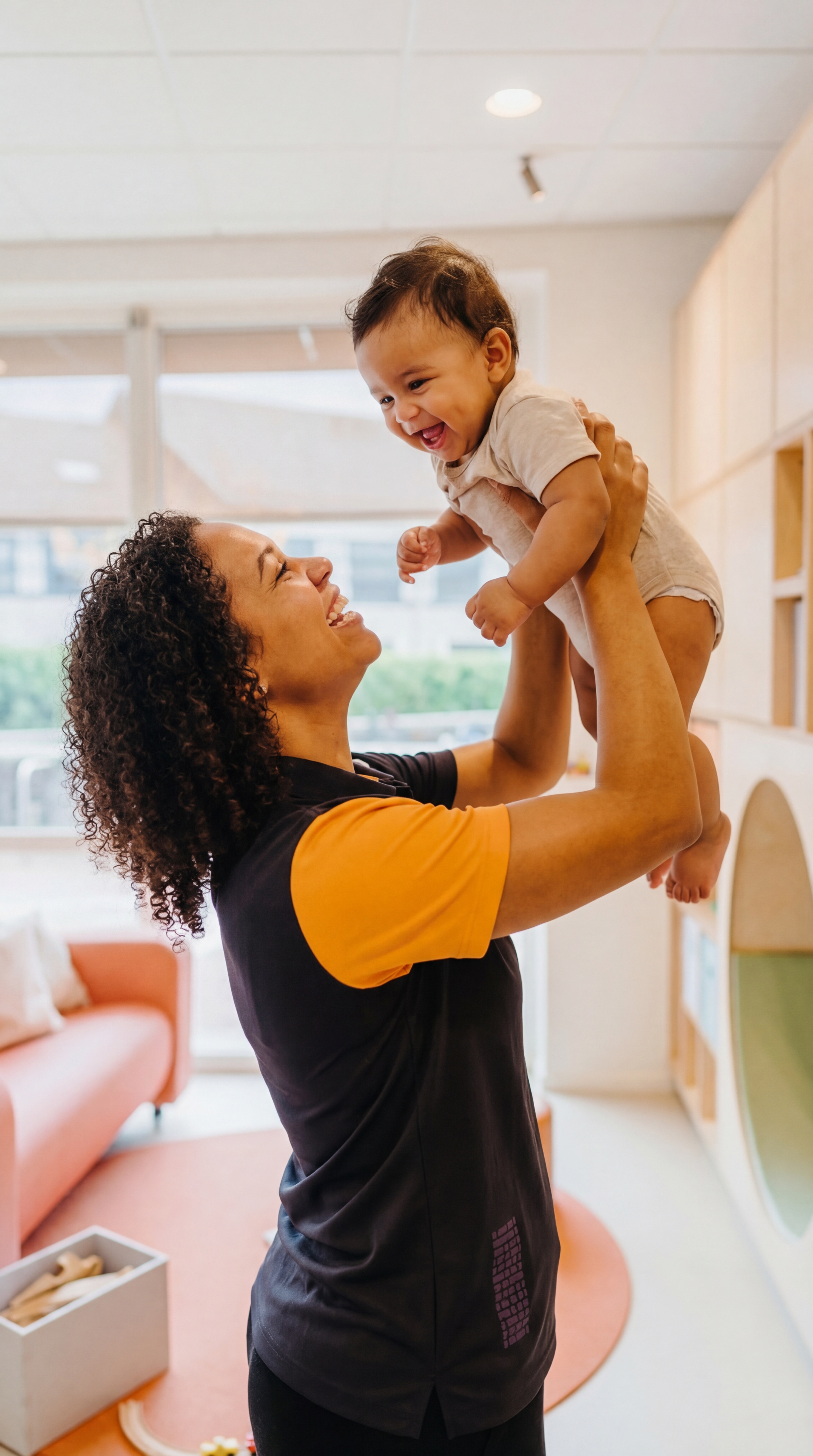 Baby wordt opgetild door pedagogisch professional op kinderdagverblijf van gro-up