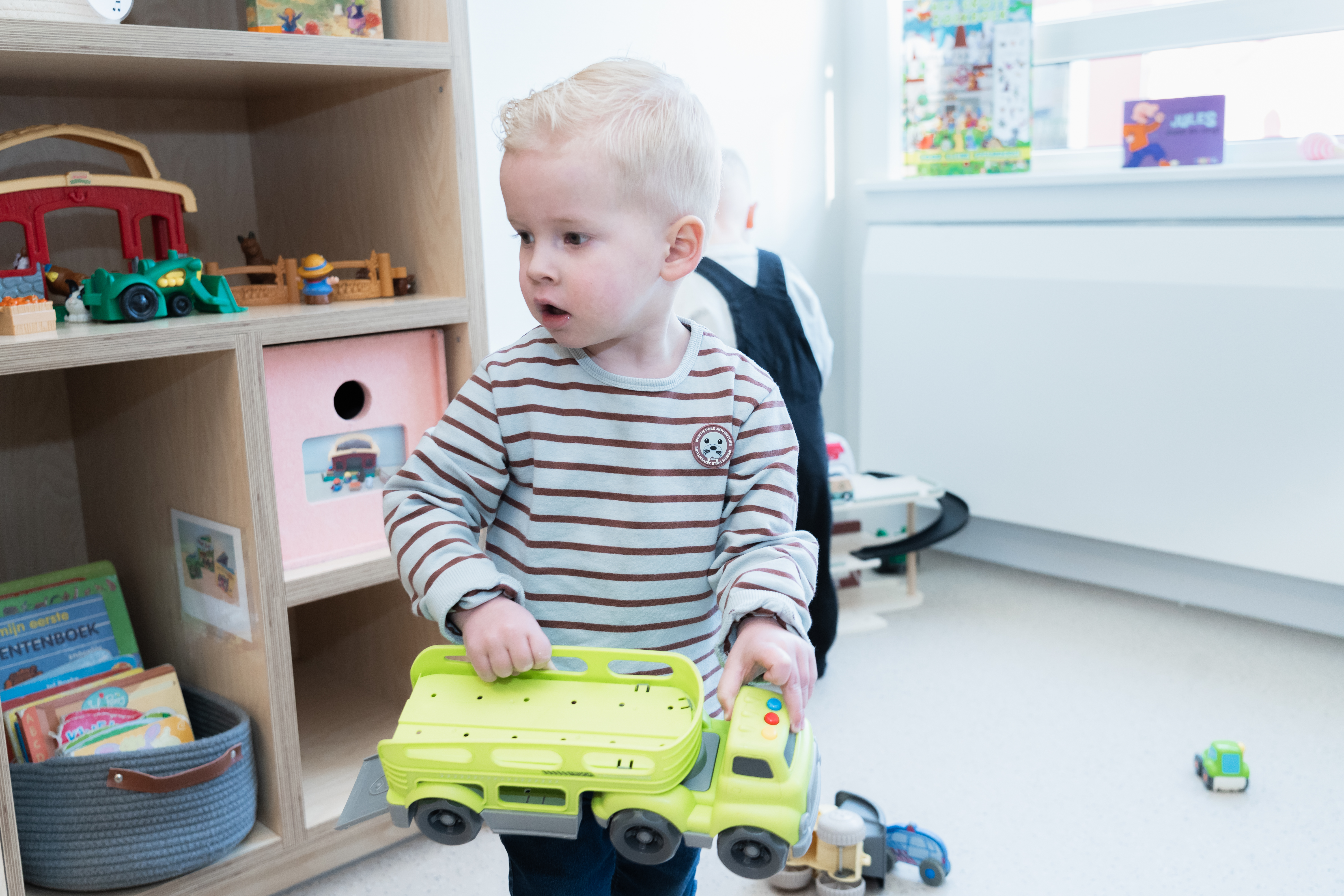 Een jongen loopt met een speelgoed vrachtwagen door peuteropvang Parelmoer van gro-up
