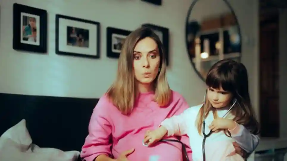 kind met stethoscoop luistert naar zwangere moeder  Zo Laat Je Je Kind Wennen Aan Een Nieuw Broertje Of Zusje