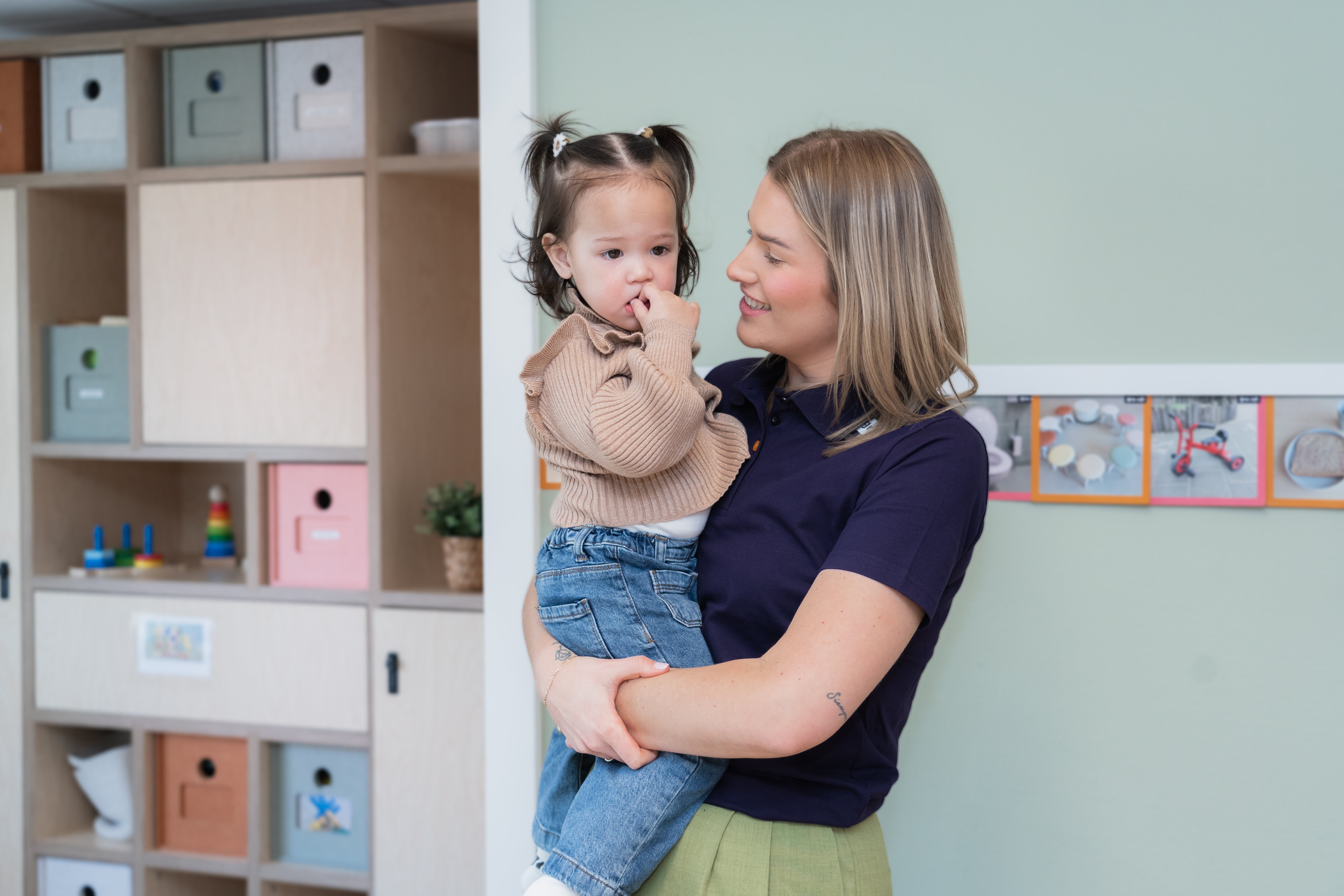 Een pedagogisch medewerker troost en dreumes die ze opgetild heeft op kinderdagverblijf Kleinkunst van gro-up