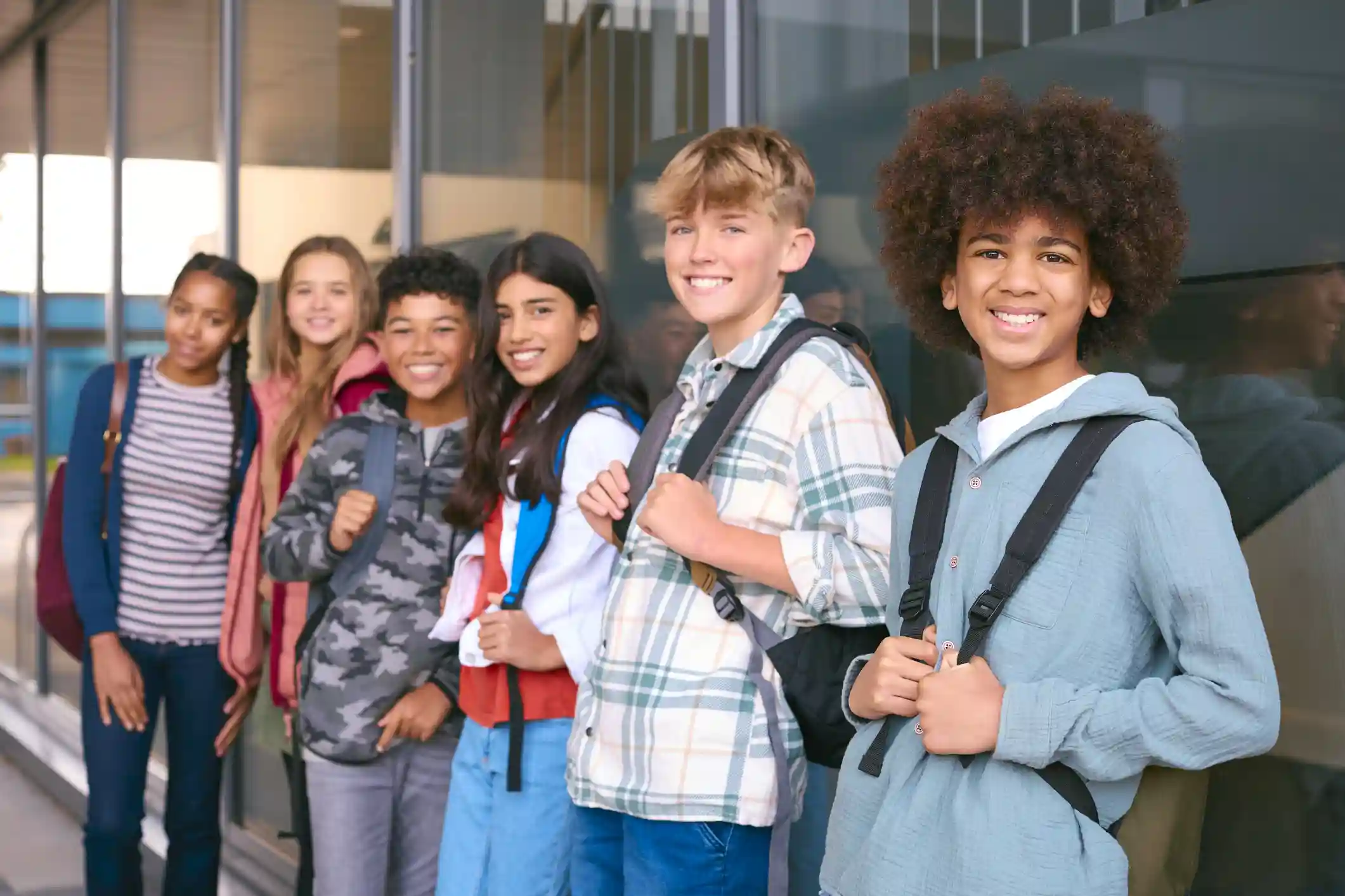gro-up jeugd Groepje middelbareschooljongeren leunt tegen de muur in de gang