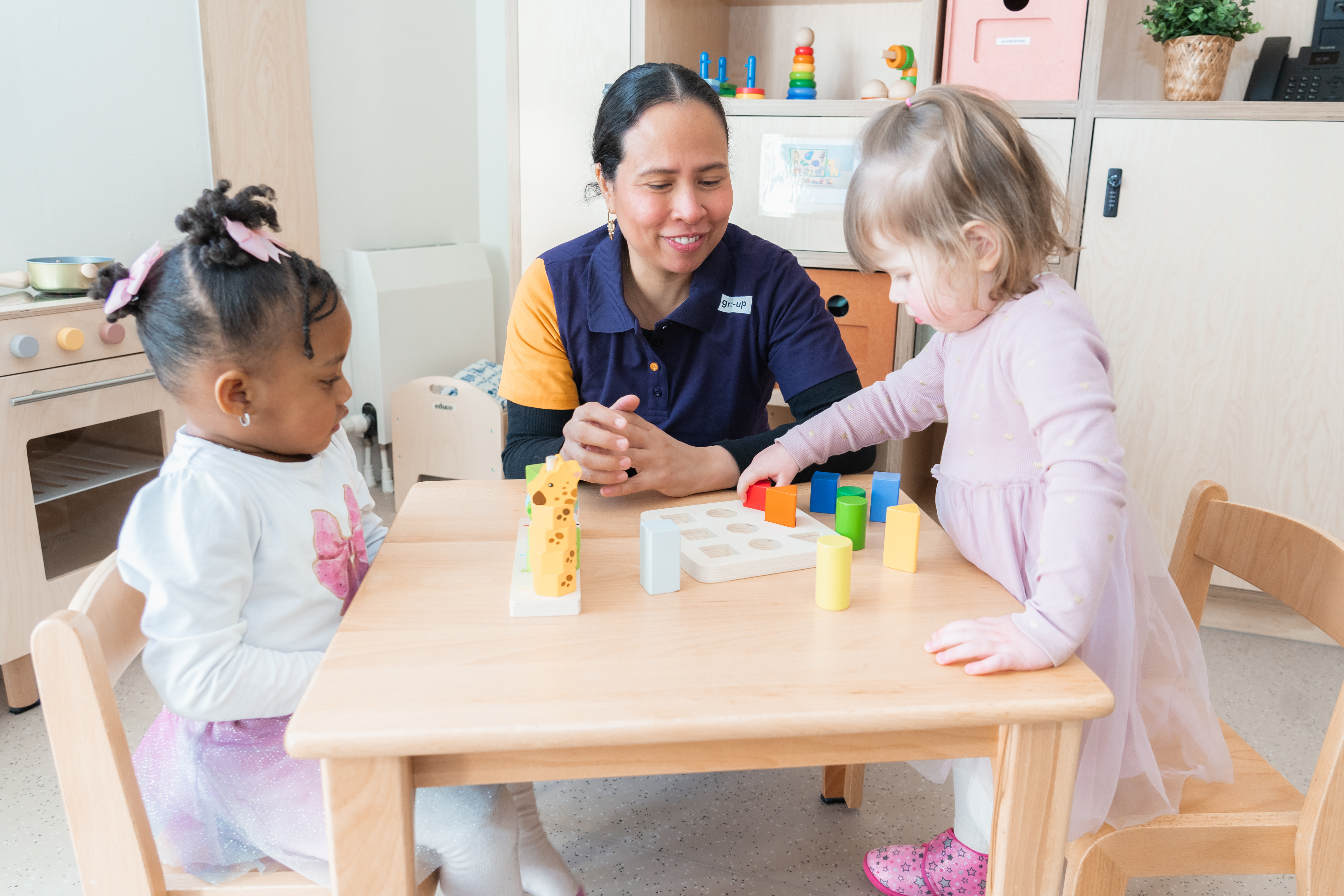 Pedagogisch medewerker observeert een meisje dat met blokken speelt op kinderdagverblijf Hillegonda's Tuin van gro-up