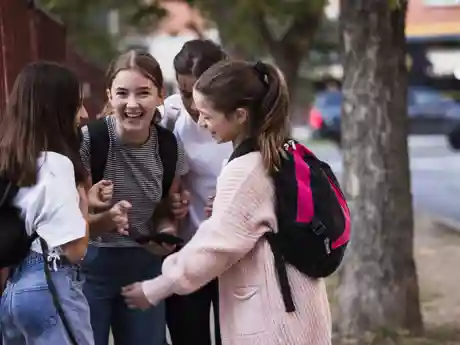 Meidenvenijn Een groepje tienermeisjes lacht met elkaar op straat