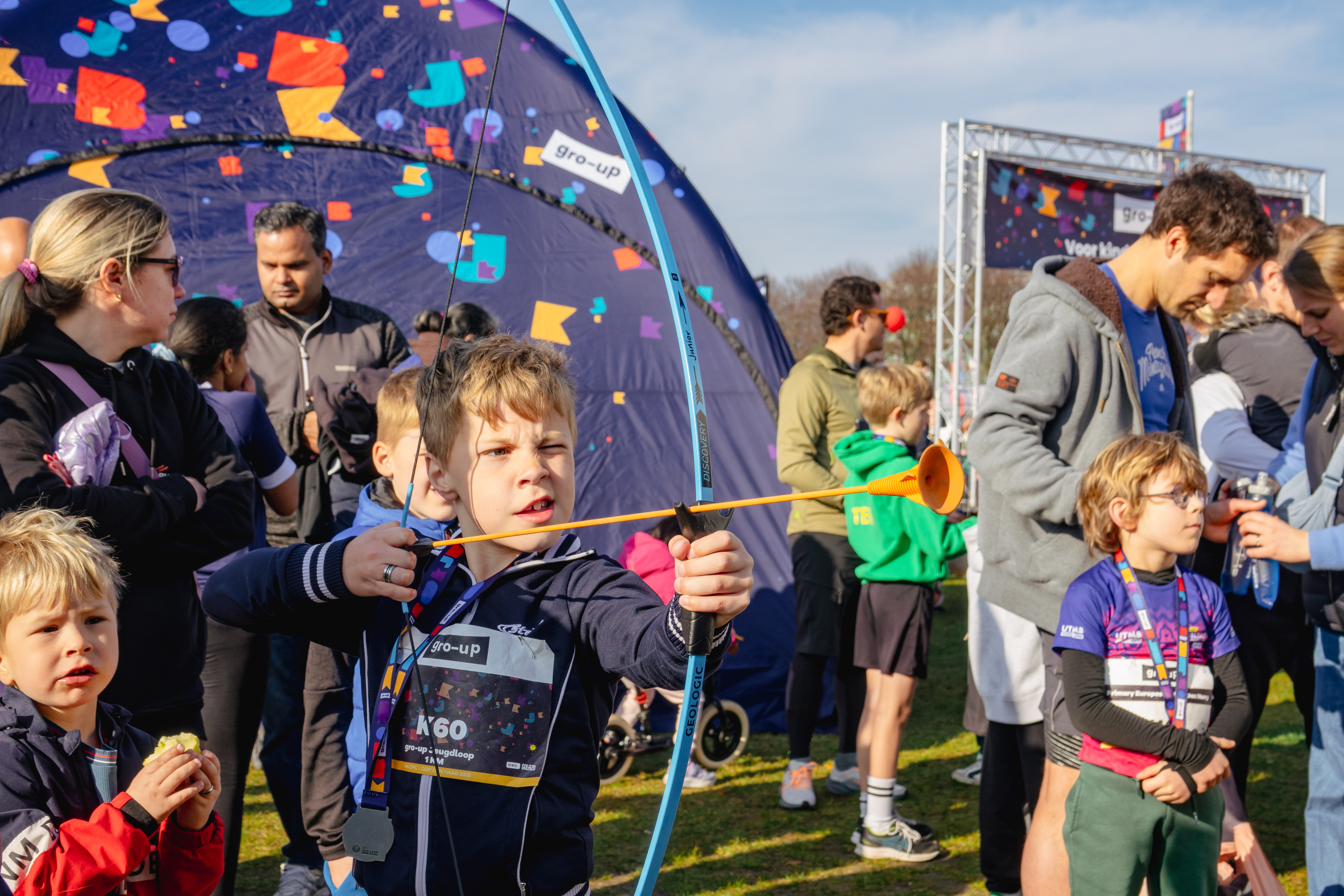 Een jongen boogschiet in de kids corner bij de gro-up Jeugdlopen van de CPC Loop Den Haag