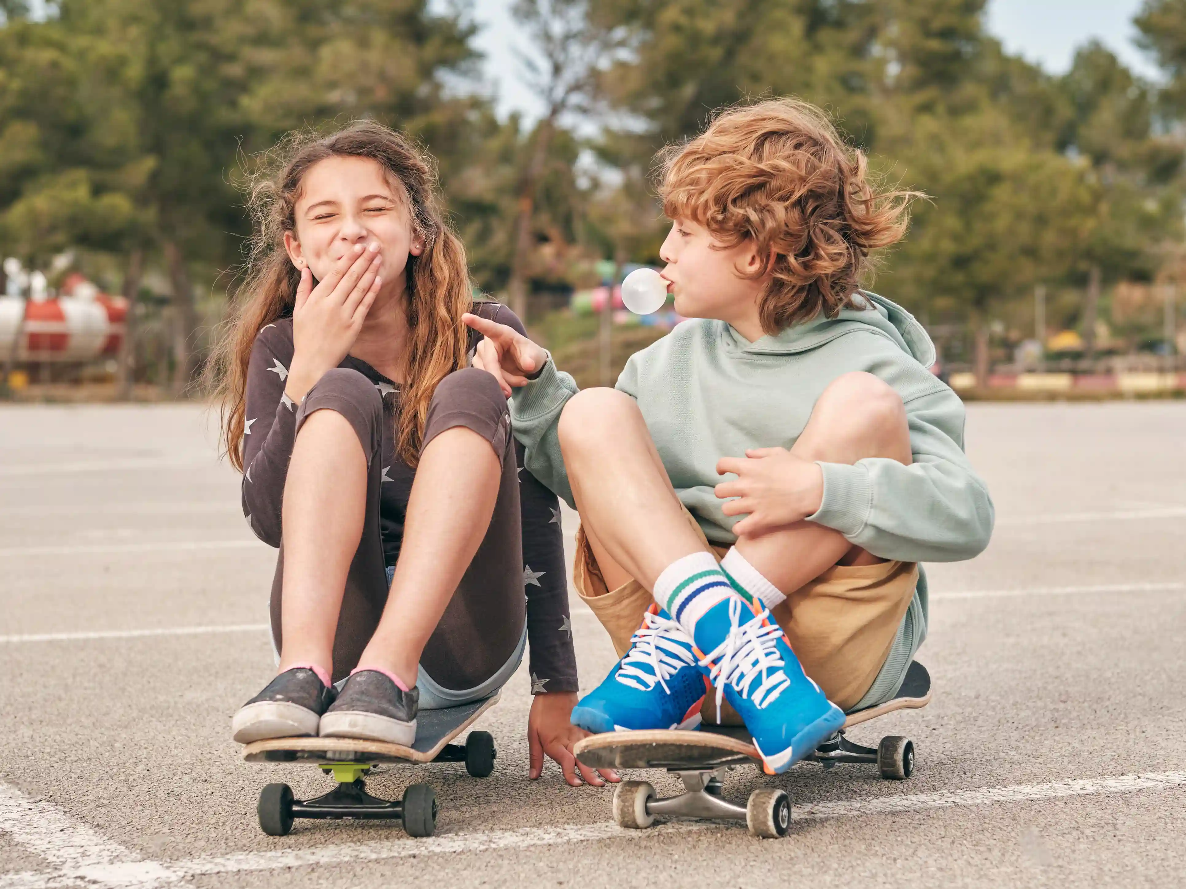 Kind- en jongerenwerk bij gro-up Een jongen en meisje zitten op een skateboard en lachen met elkaar