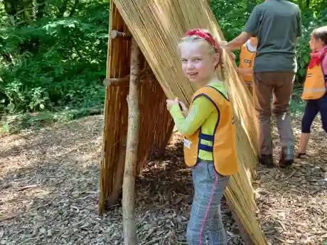 gro-up meisje bouwt een hut tijdens de campingweek