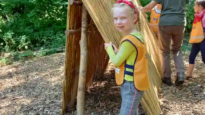 gro-up meisje bouwt een hut tijdens de campingweek