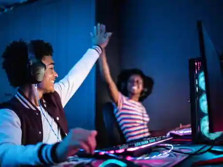 Mediawijsheid in de buurt Een gamende jongen en meisje geven elkaar een high five