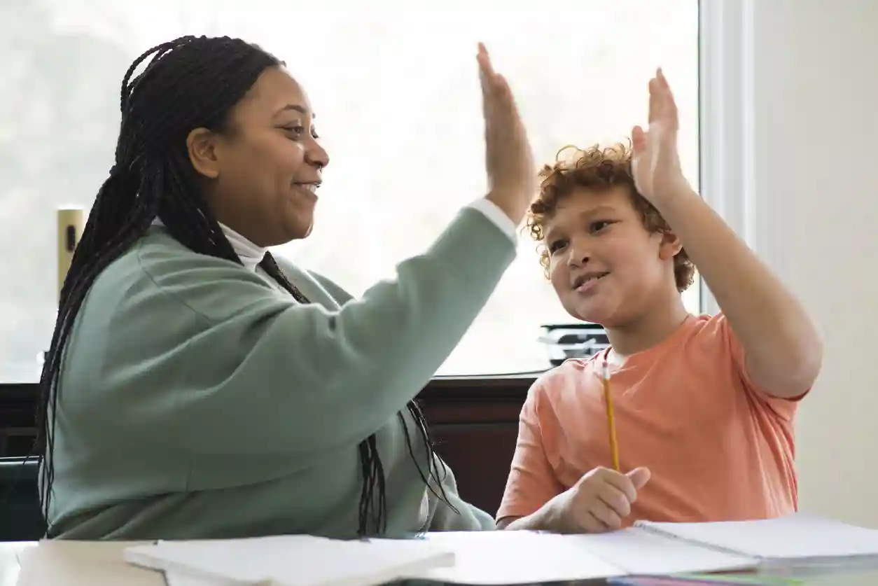 Schoolbegeleiding voor jongeren van gro-up jeugdhulp gro-up jeugdhulpverlener geeft een high five aan een jongen die schoolbegeleiding krijgt