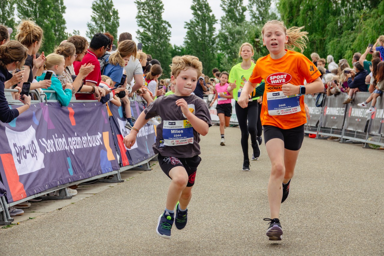 Een jongen en een meisje rennen de gro-up Lint-Wurmpie Run in Utrecht