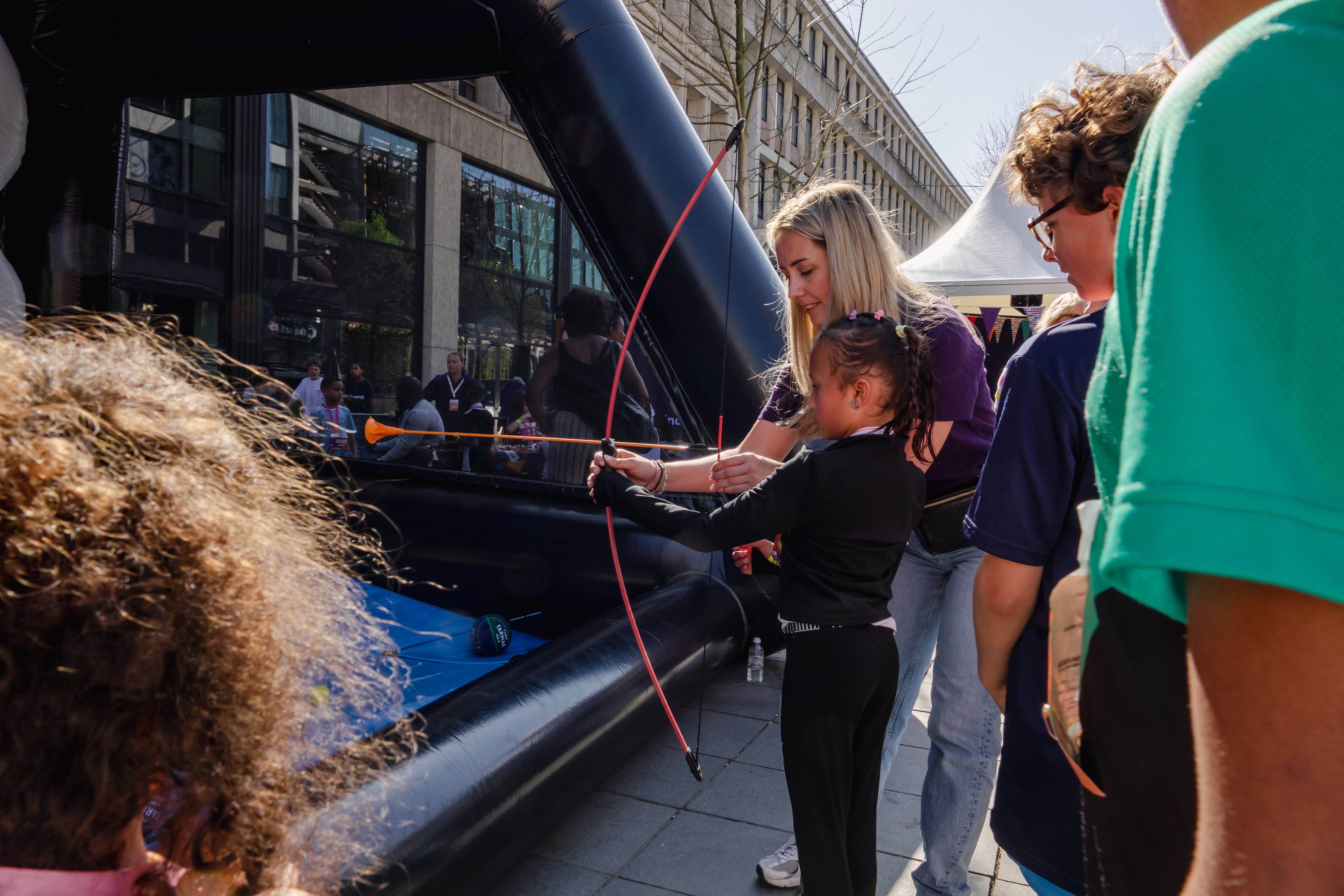 Een meisje krijgt uitleg over boogschieten in de kids corner van gro-up tijdens de NN Kids Run van de Marathon Rotterdam
