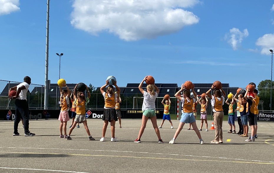 gro-up kinderen spelen basketbal tijdens de zomerspelen