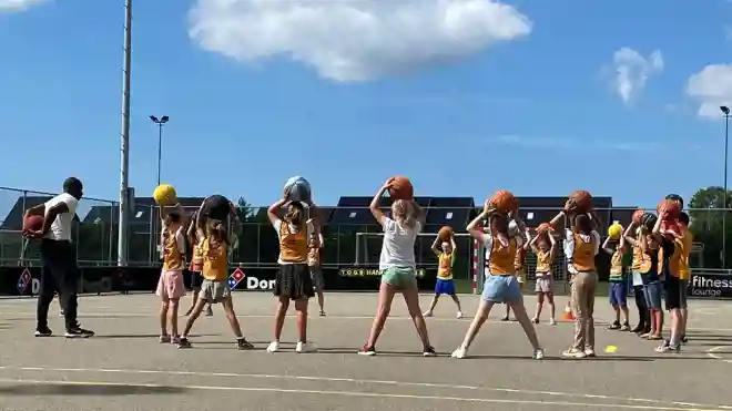 gro-up kinderen spelen basketbal tijdens de zomerspelen