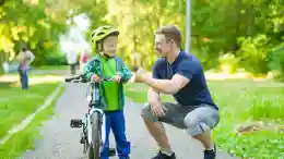 gro-up volwassene man geeft een compliment aan een jongen dat leert fietsen
