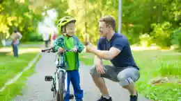 gro-up volwassene man geeft een compliment aan een jongen dat leert fietsen