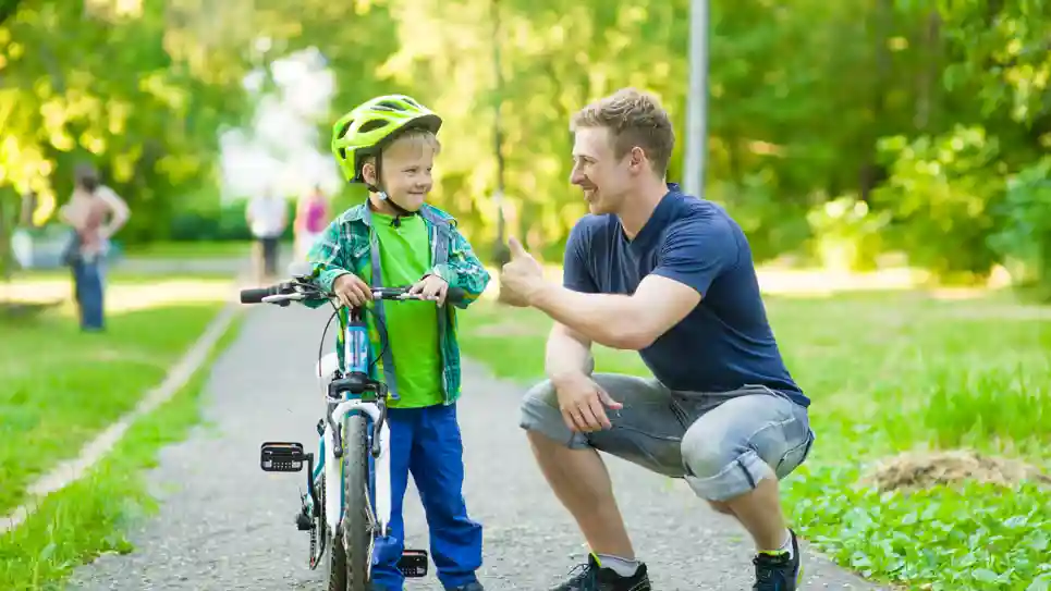 gro-up volwassene man geeft een compliment aan een jongen dat leert fietsen gro-up volwassene man geeft een compliment aan een jongen dat leert fietsen