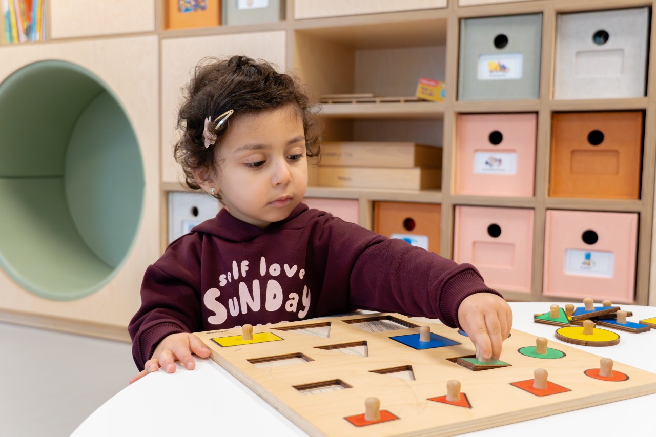 Een meisje ontdekt al spelend hoe vormen in elkaar passen op Peuteropvang Paddington van gro-up