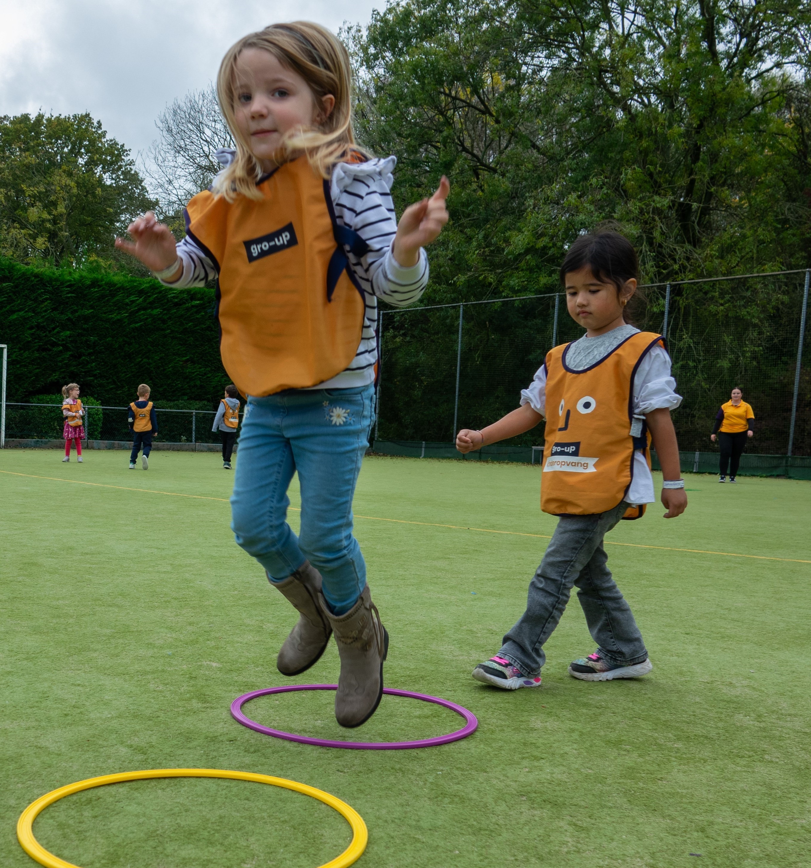 Kind spring van hoepel naar hoepel tijdens een sportieve middag op buitenschoolse opvang Bij de sport van gro-up
