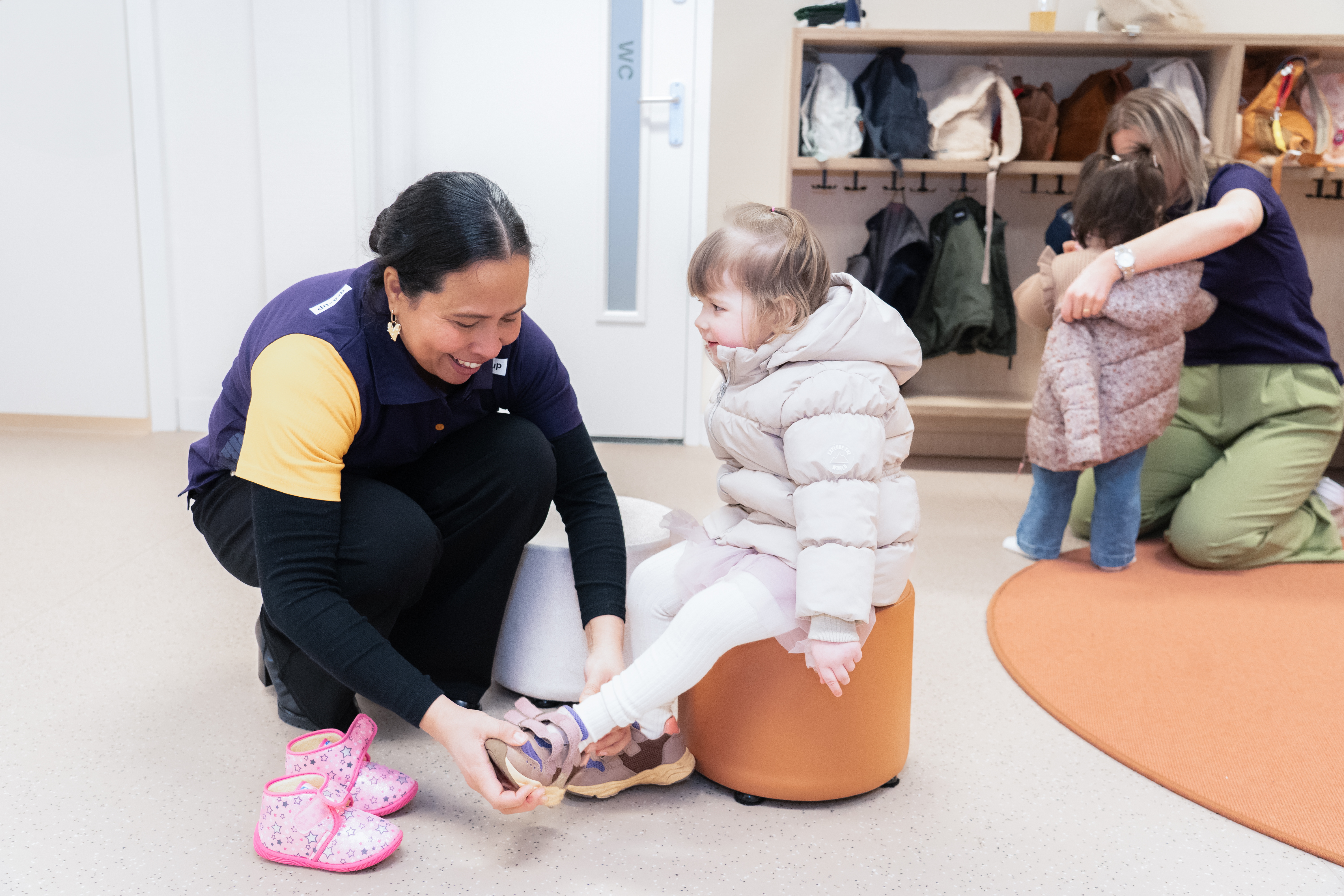Pedagogisch medewerker helpt een meisje haar schoenen aantrekken bij peuteropvang Nansenplaats van gro-up
