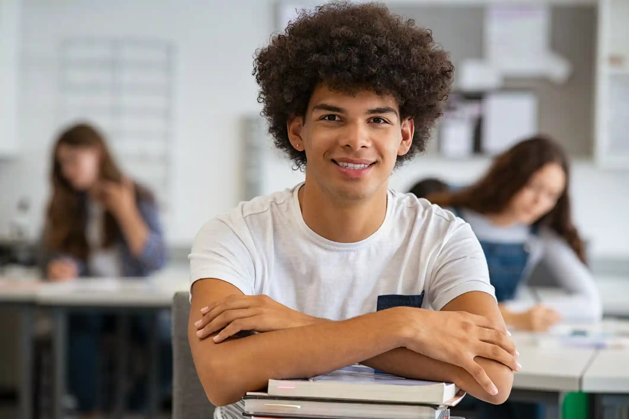 Het Geheim Dat Elke Middelbare Scholier Moet Kennen Jongen leunt op schoolboeken in een klas