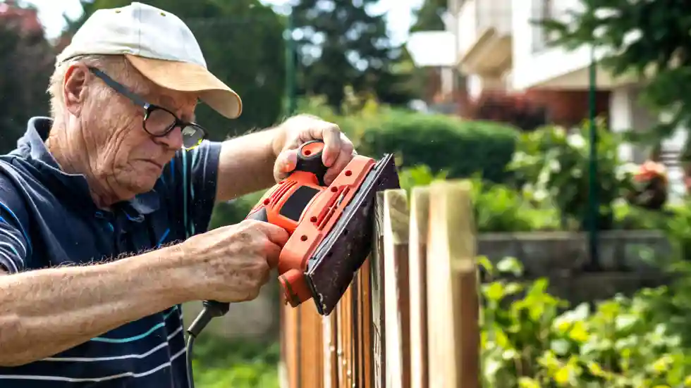 DemenTalent Een oude man schuurt een schutting als onderdeel van DemenTalent van gro-up buurtwerk
