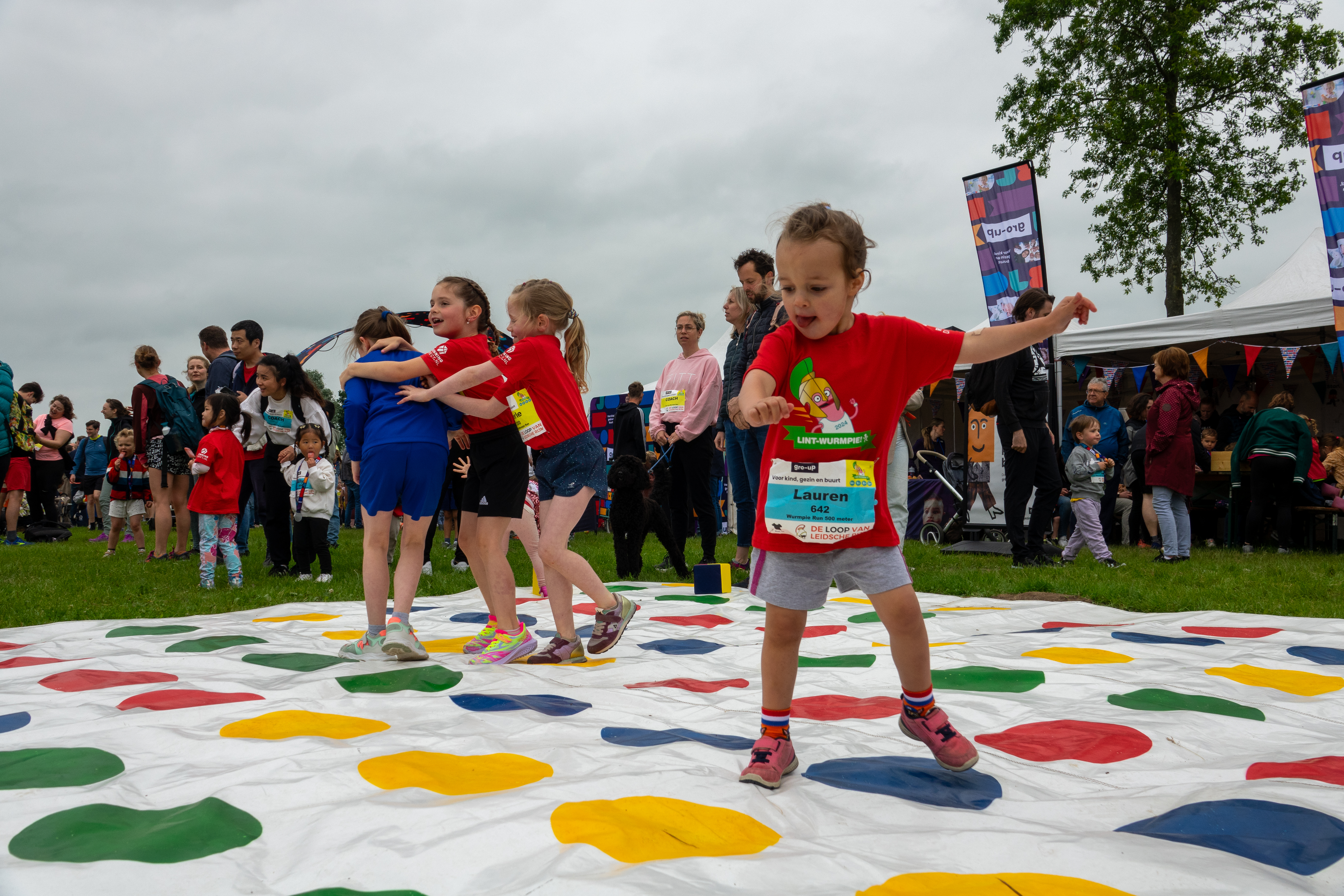 Vier meisjes spelen levensgroot Twister in de kids corner tijdens de gro-up Lint-Wurmpie Run