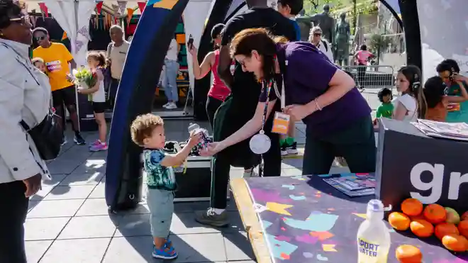 gro-up Kids Run Marathon Rotterdam Kids Corner fruit uitdelen Een jongetje krijgt een bidon van een pedagogisch medeweker in de kids corner van gro-up tijdens de NN Kids Run van de Marathon Rotterdam