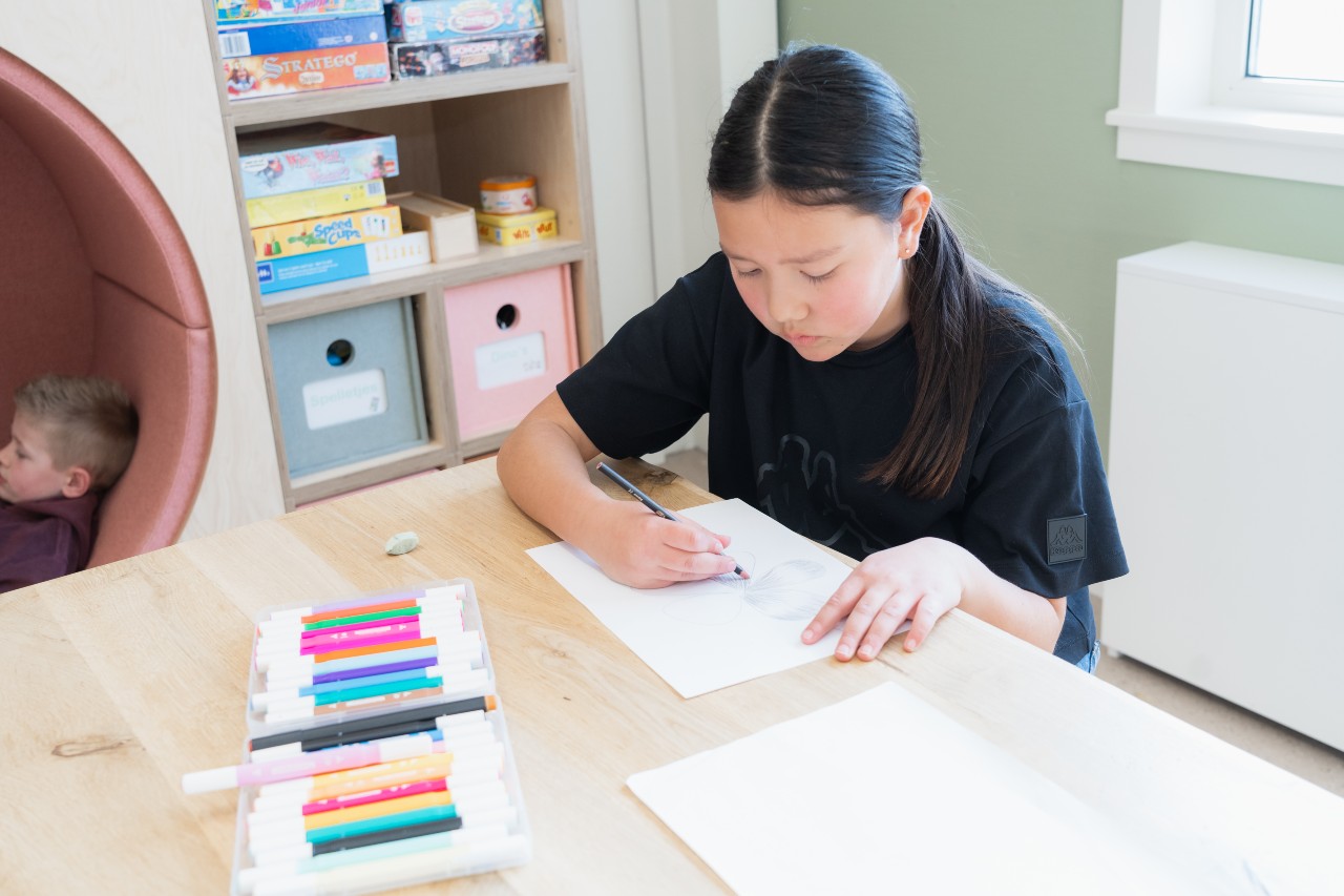 Een meisje zit te tekenen terwijl een jongen ligt te lezen op BSO Het Eendennest Schoutenhoek in Zoetermeer Palenstein