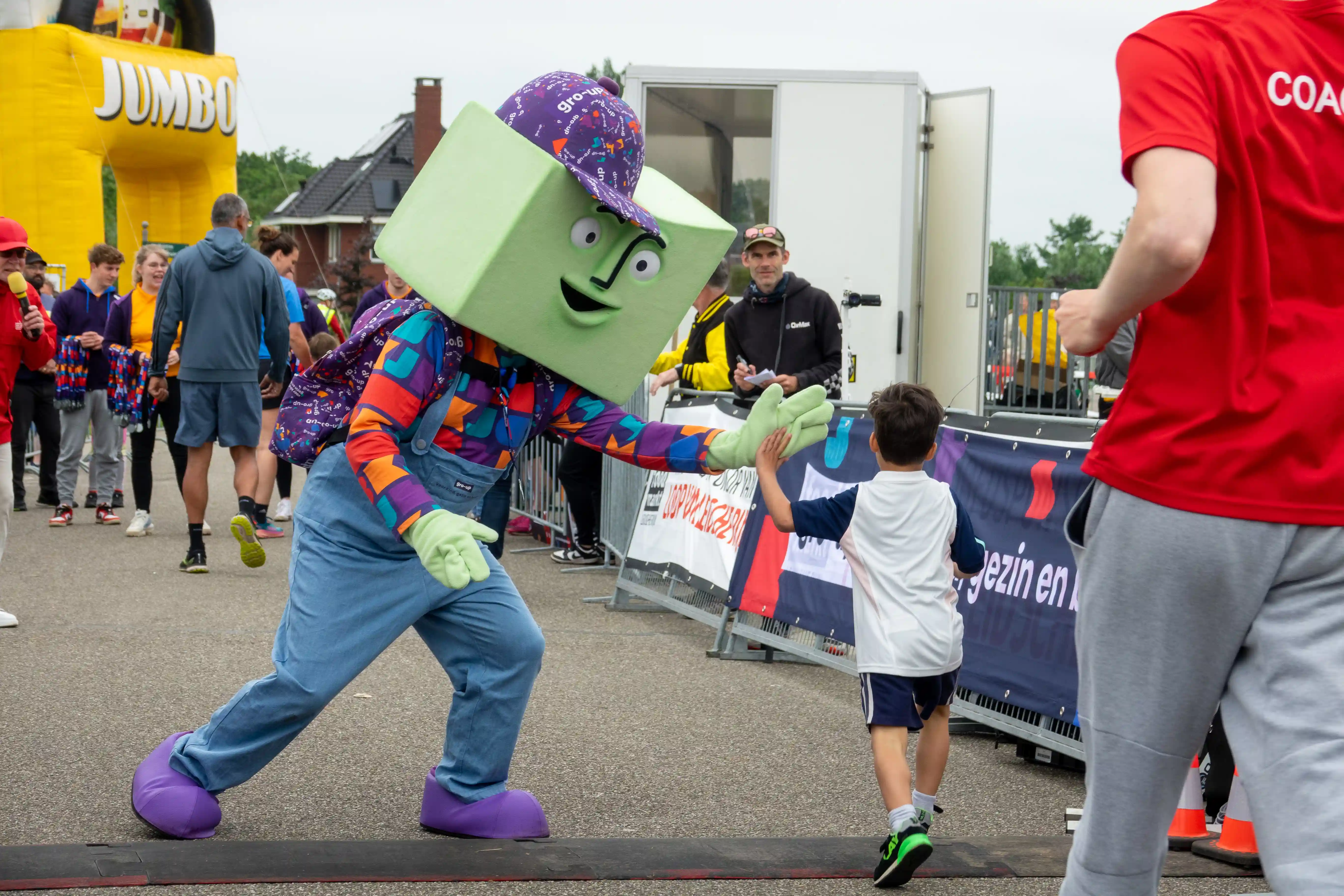 Mascotte grup van gro-up high fivet een kind tijdens de Lint-Wurmpie Run