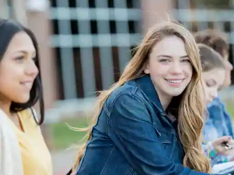 Girls Talk Blond meisje lacht in de camera, ze zitten tussen een groep meiden
