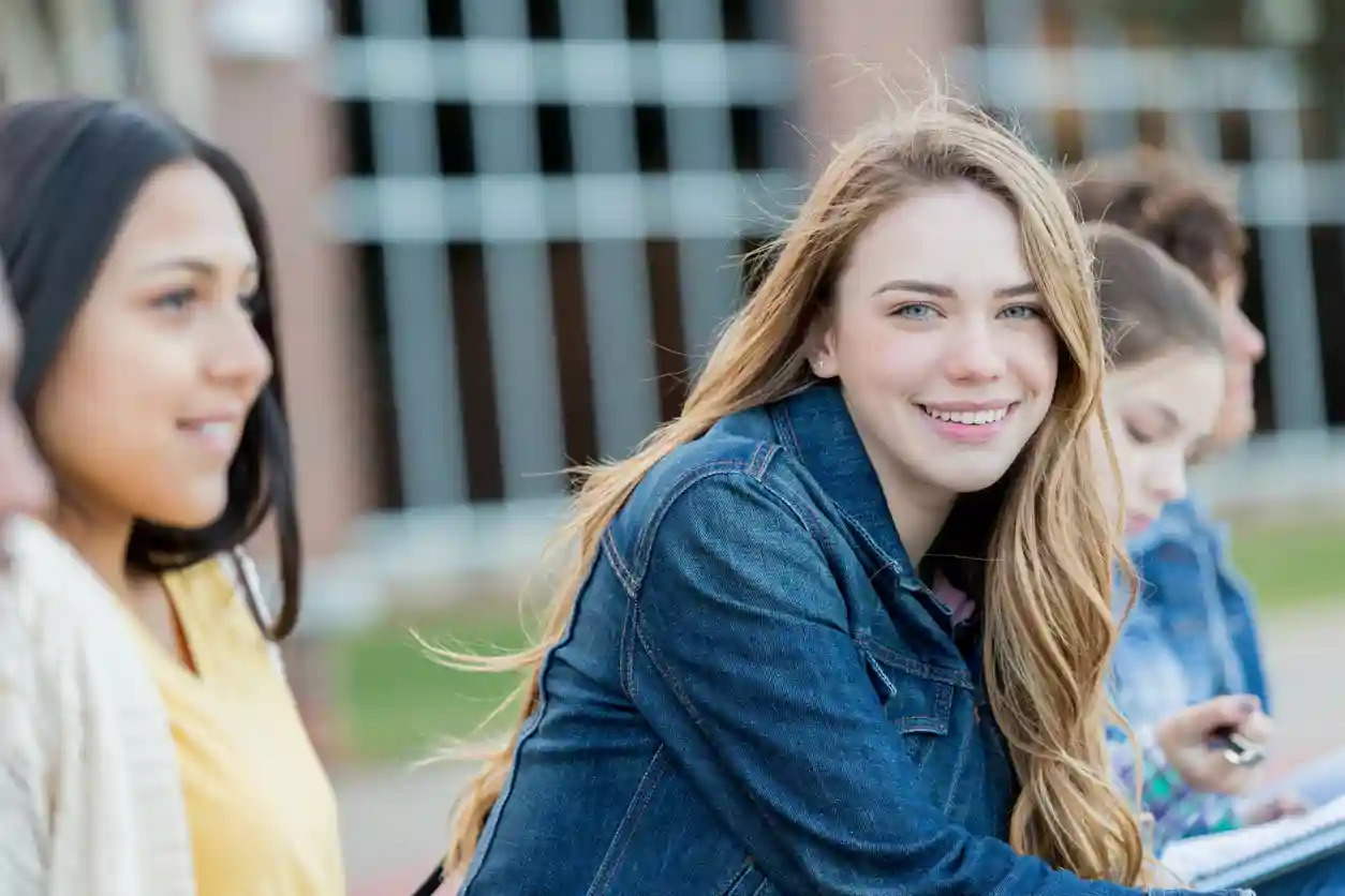 Girls Talk Blond meisje lacht in de camera, ze zitten tussen een groep meiden