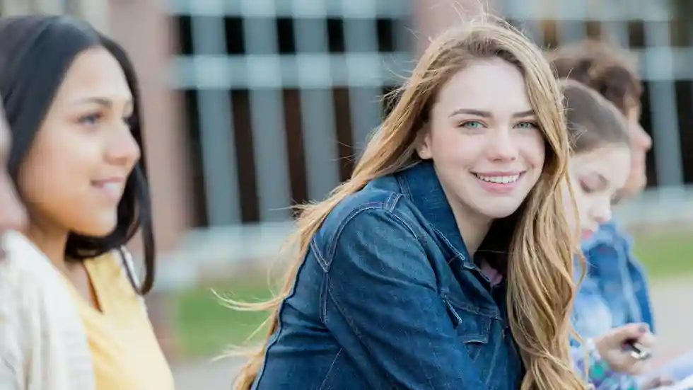 Girls Talk Blond meisje lacht in de camera, ze zitten tussen een groep meiden