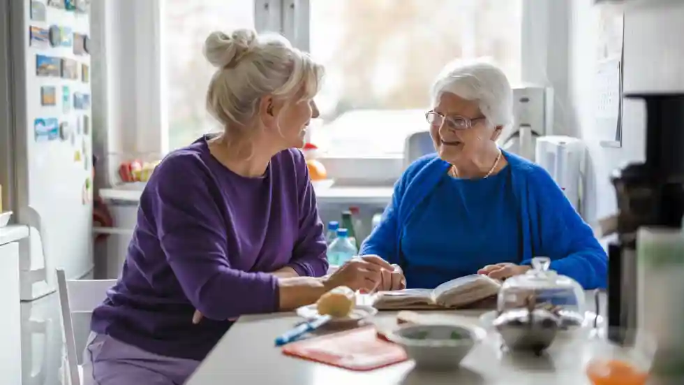 Mantelzorgsupport Een dame helpt een oudere dame met lezen en eten
