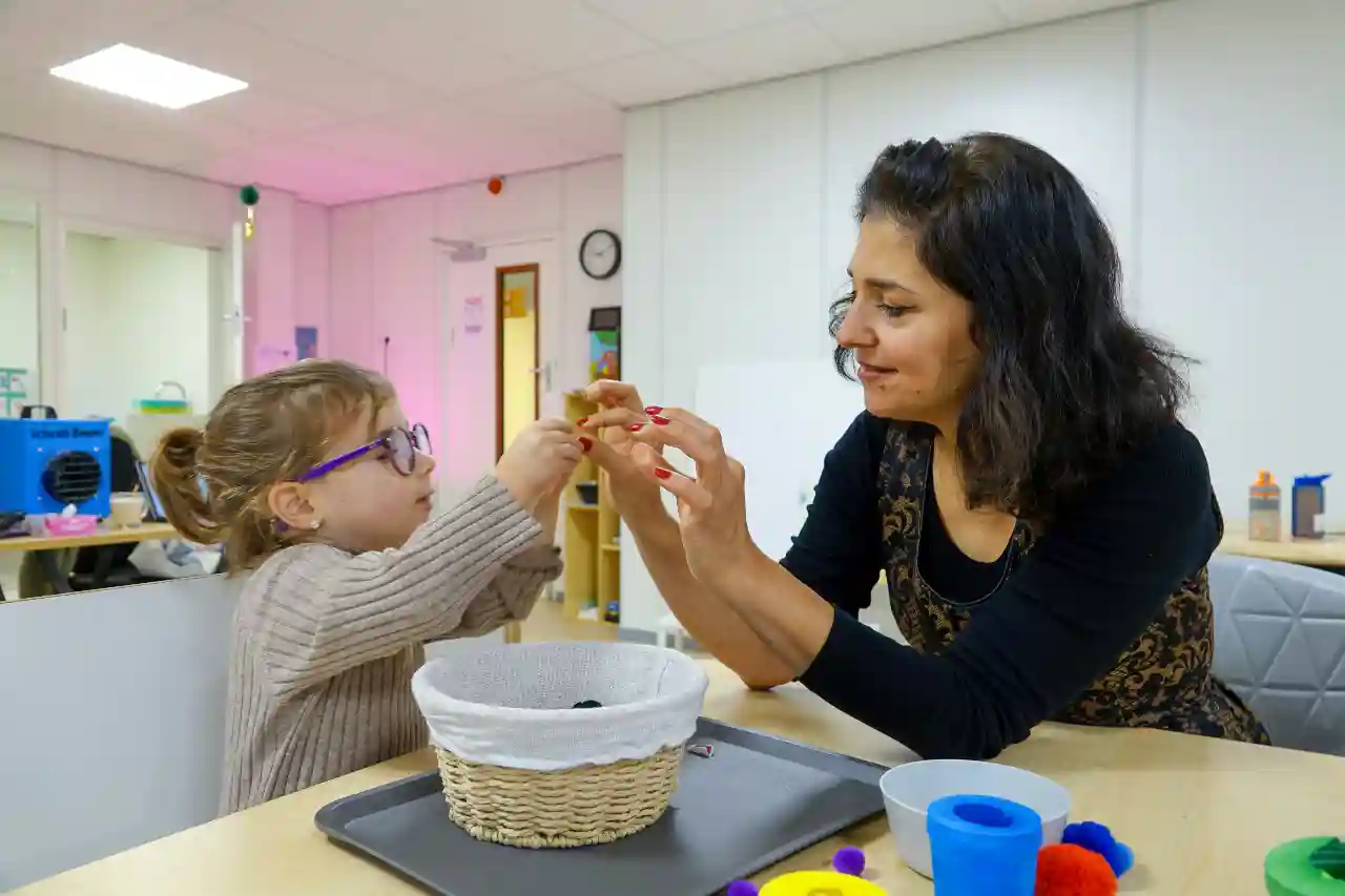 Meisje (peuter-kleuter) knutselt met pedagogisch medewerker