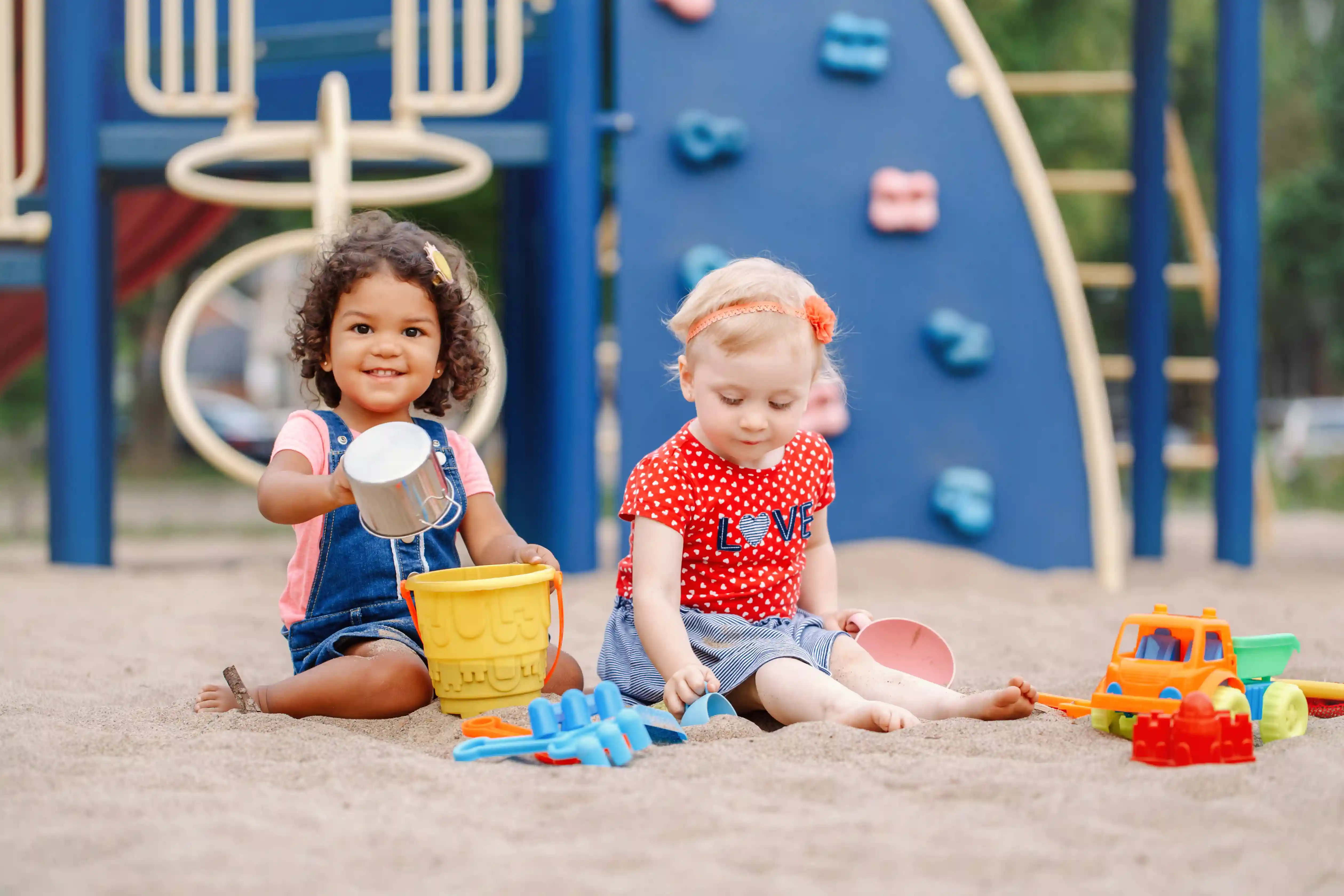 Twee meisjes (peuter-kleuter) spelen in de zandbak