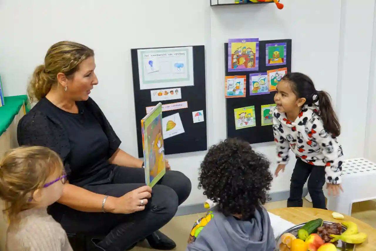 Pedagogisch medewerker leest peuter-kleuter voor op het kinderdagverblijf