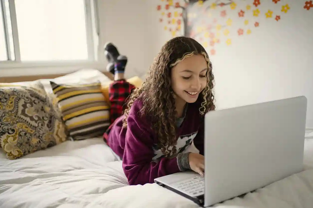 Meisje ligt met laptop op bed