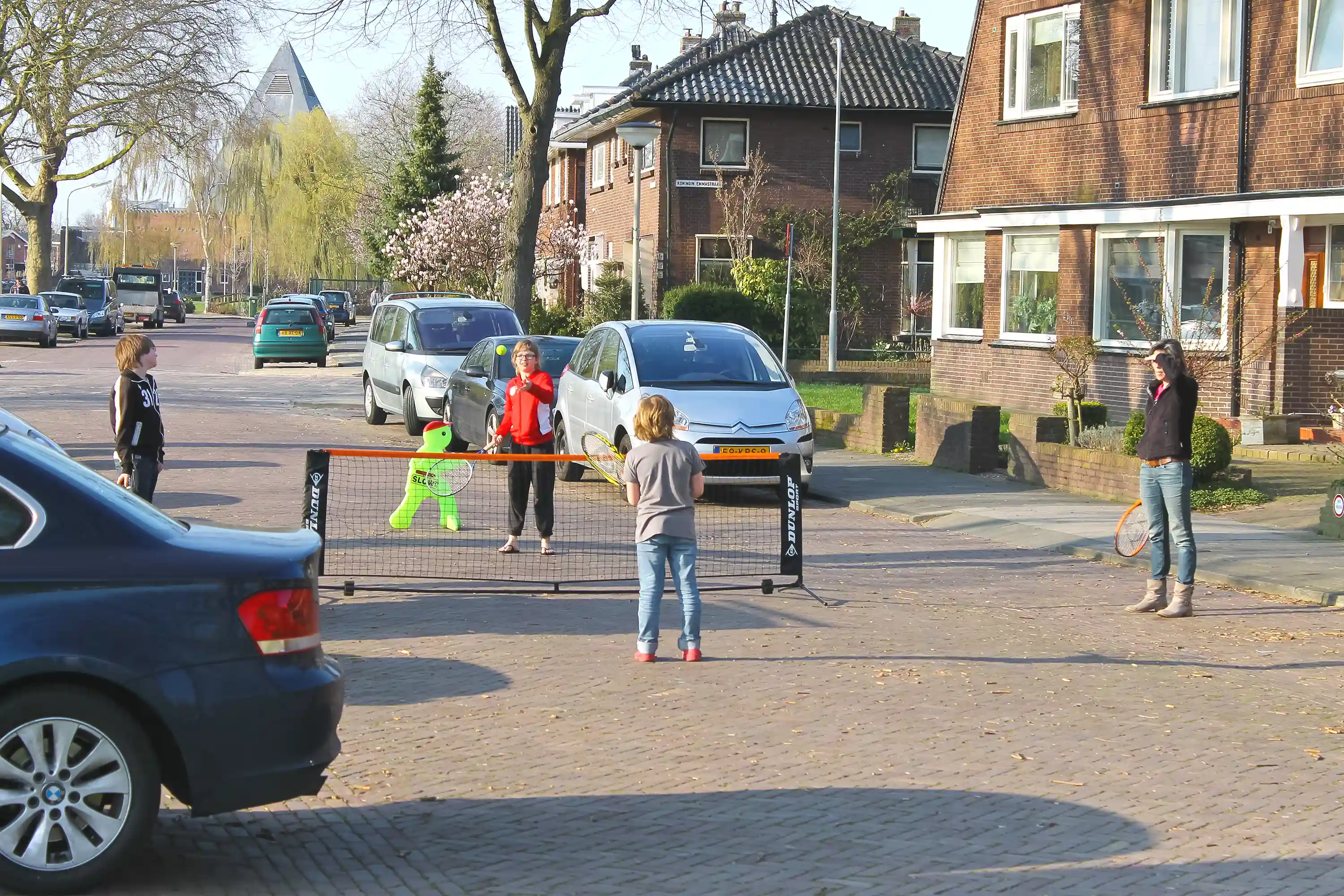 Onze buurten Krimpen aan den IJssel Drie kinderen en volwassen vrouw batmintonnen op straat in Krimpen aan den IJssel