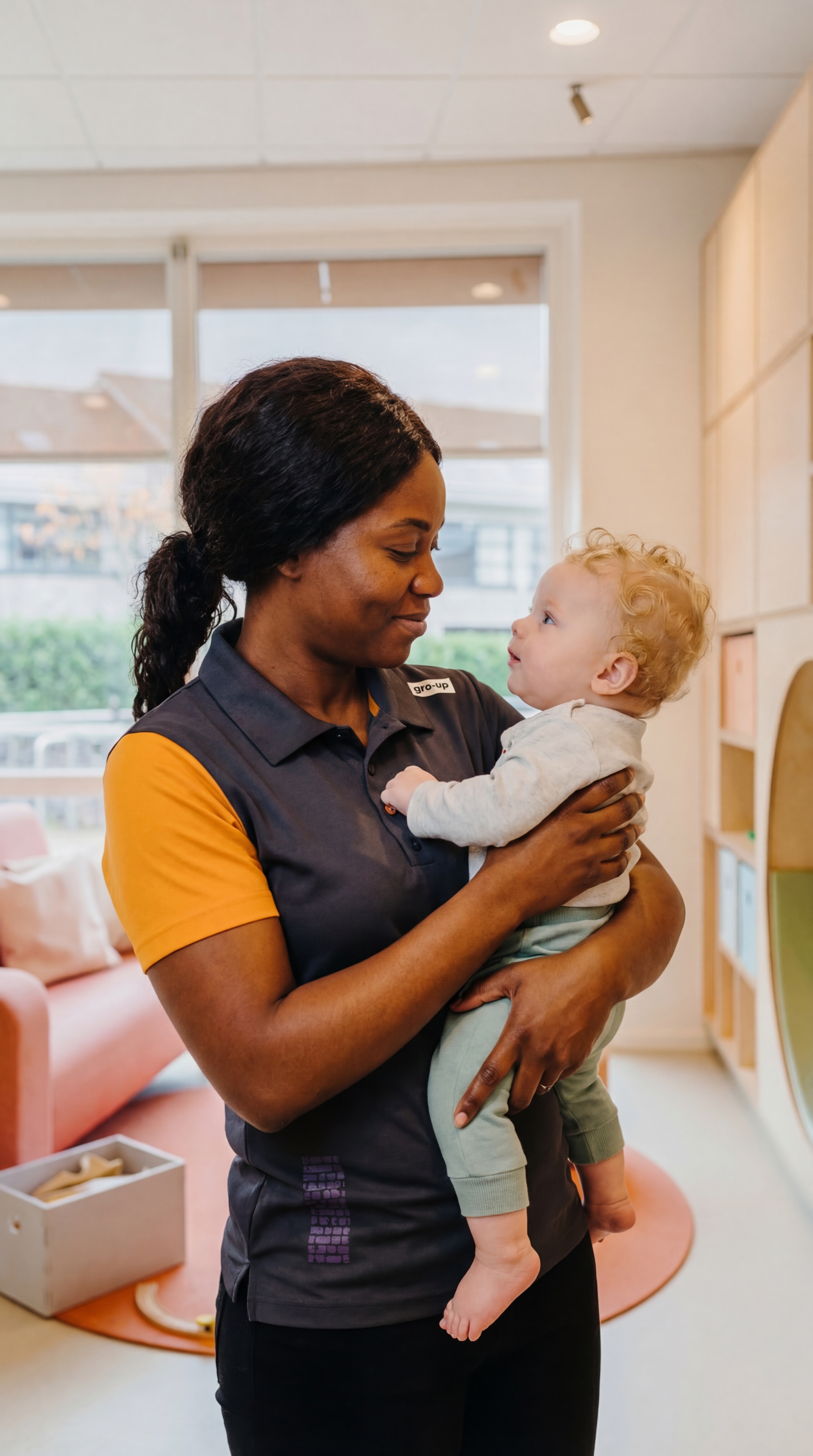 gro-up kinderdagverblijf pedagogisch professional houdt baby vast