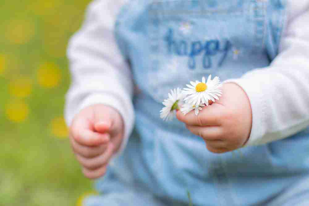 Baby met bloemen in handen