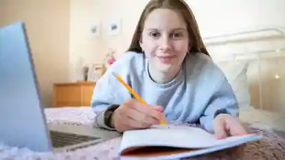 gro-up jeugd meisje maakt huiswerk op bed