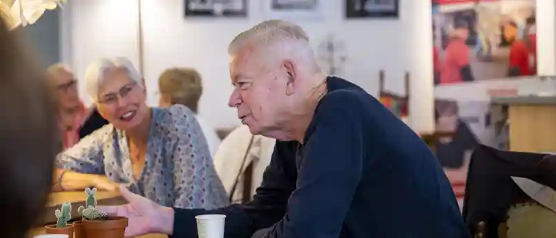 gro-up buurtwerk Huis van de Wijk Rendierhof Een oudere man vertelt aan leeftijdsgenoten in Huis van de Wijk Rendierhof van gro-up buurtwerk