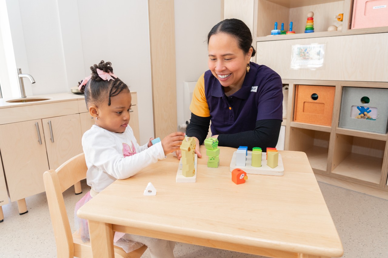 Een pedagogisch professional helpt een meisje met bouwen bij peuteropvang Kiekeboe van gro-up in Linschoten