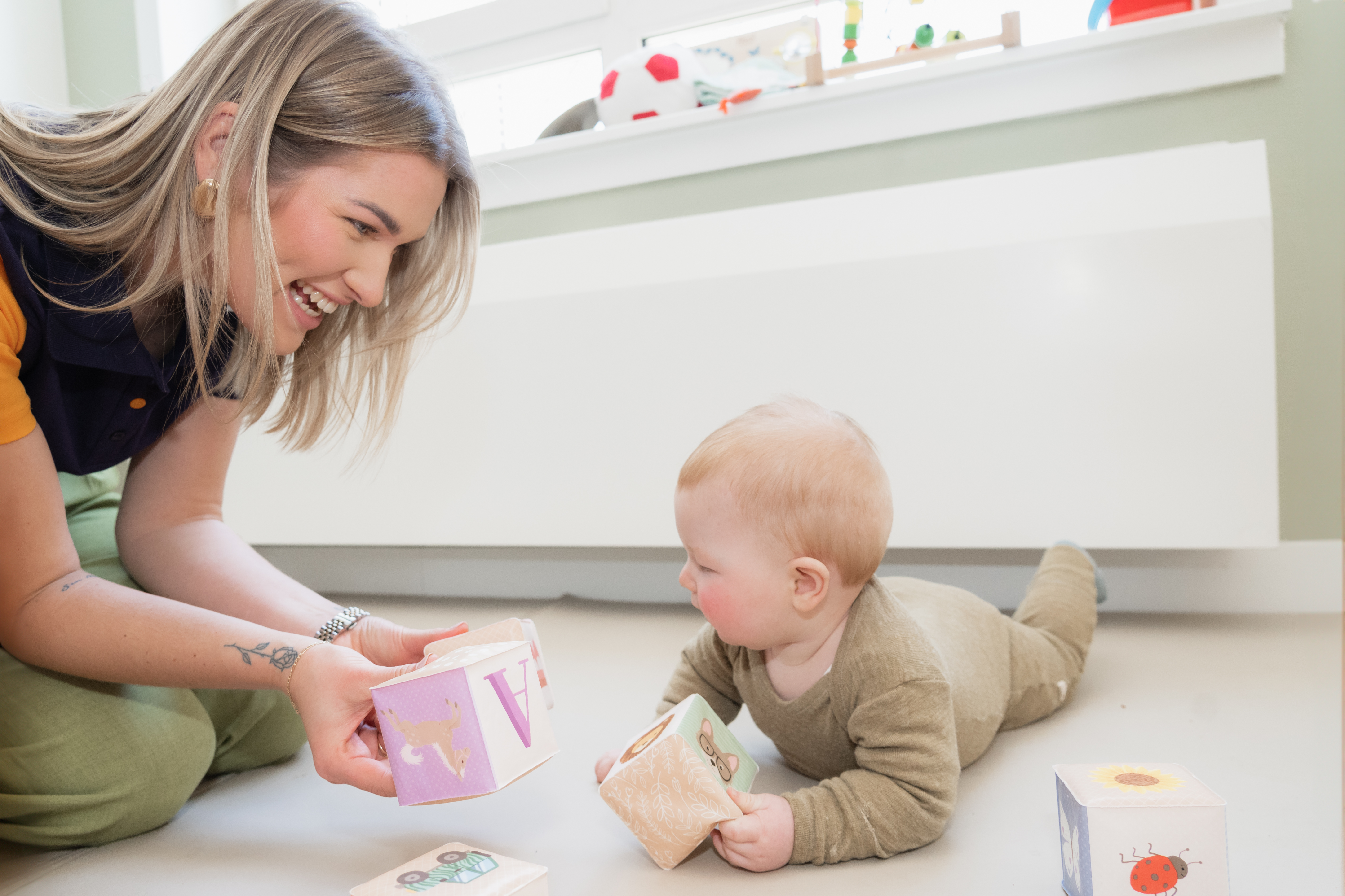 Pedagogisch medewerker speelt met een baby op kinderdagvebrlijf Toverkunst van gro-up