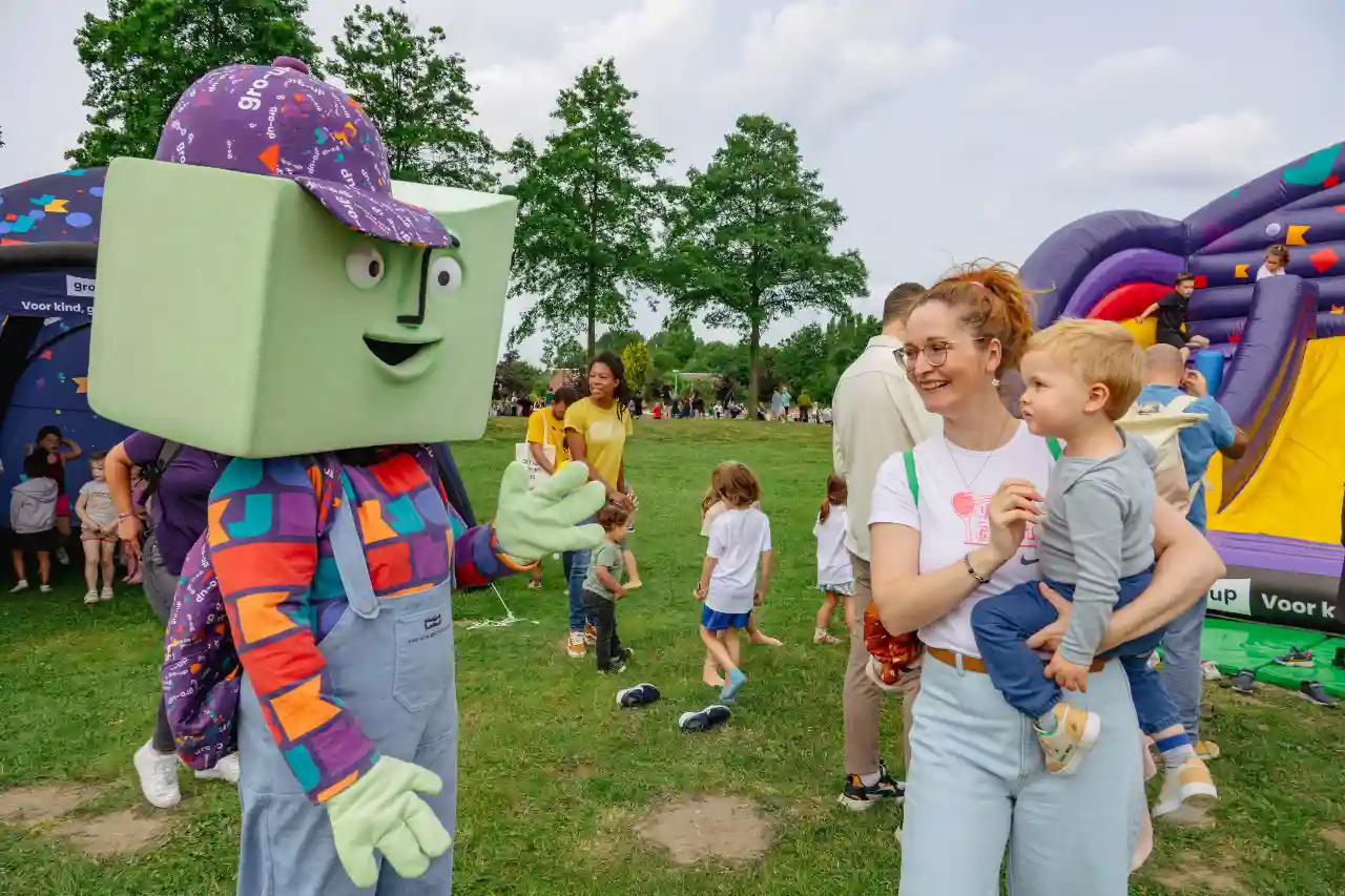 Een peuter op de arm bij moeder ontmoet mascotte grup tijdens de gro-up Lint-Wurmpie Run