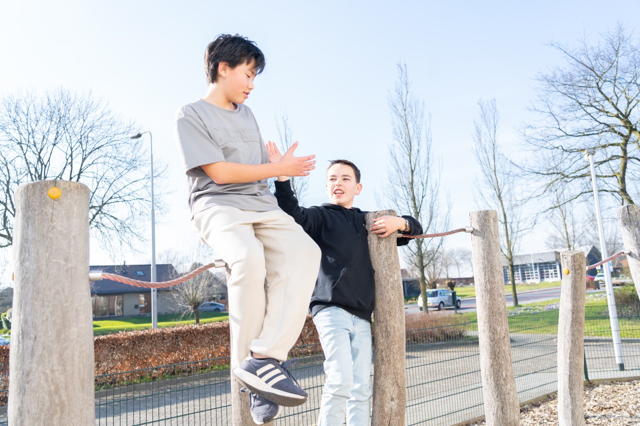 Twee jongens groeten elkaar op het klimrek buiten bij BSO Het Kwartelnest van gro-up in Zevenhuizen