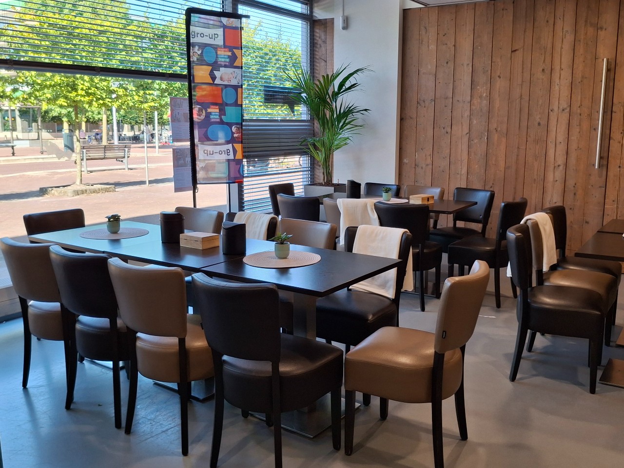 Tafels en stoelen staan klaar voor een gezellig samenzijn in Huis Van De Wijk Minervaplein van gro-up in Rotterdam Hillegersberg